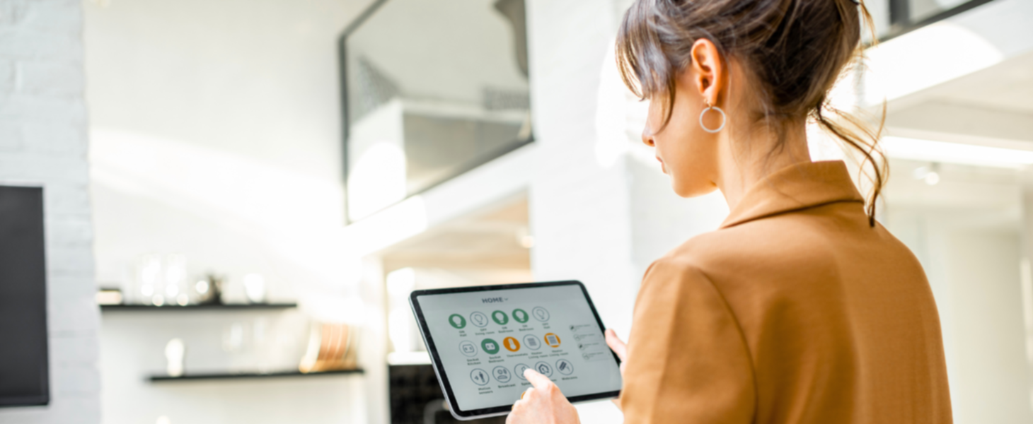 Eine Frau, die mit einem Tablet ihr Smart Home System bedient.